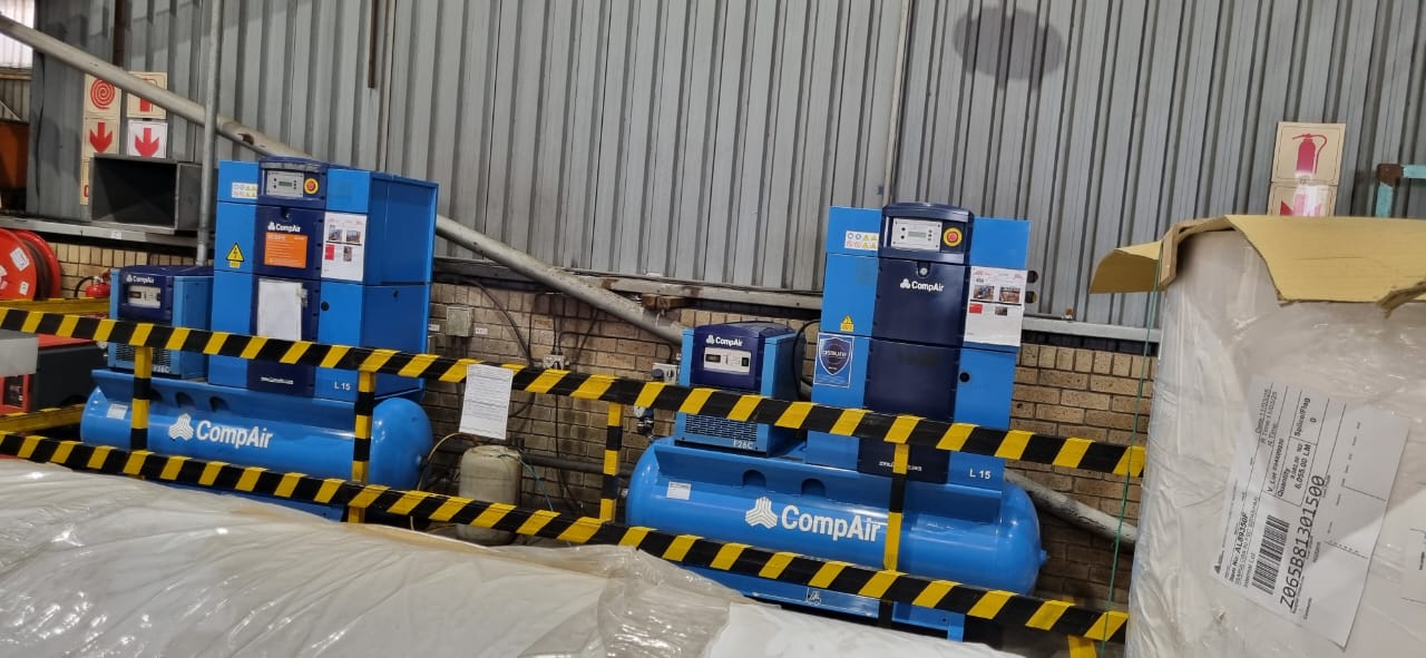 Two blue CompAir L15 compressors professionally installed behind safety barriers at a manufacturing plant in Durban by the KZN & GP Compressors team.